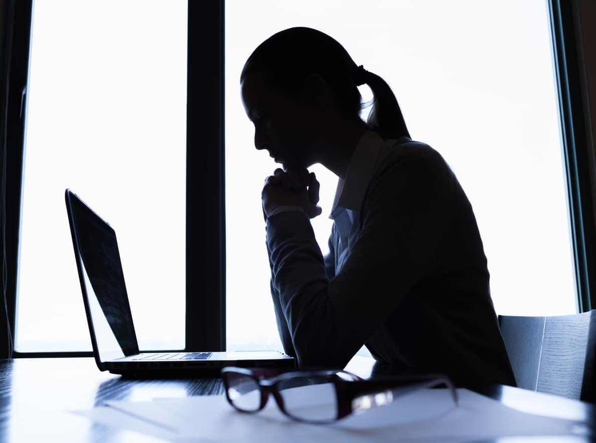 A silhouette of a woman reviewing leadership coaching help on her laptop.