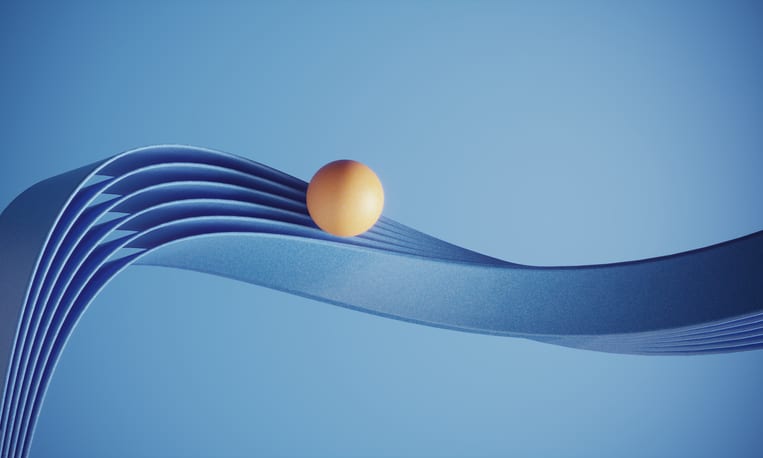 A yellow ball rolls along a blue ribbon, balancing itself.