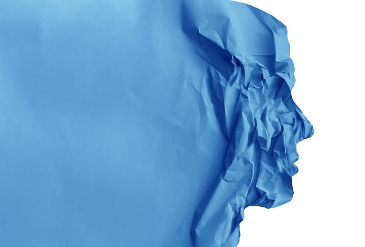 Human stress and anxiety concept as a person in panic crushed by fear and psychological pain as crumpled paper representing burnout symptoms.