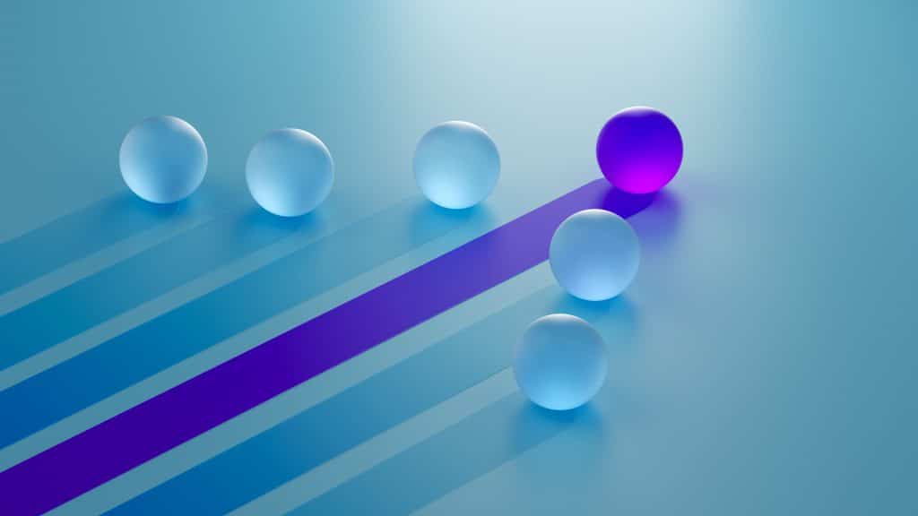 A purple sphere with a purple trail behind it is leading a group of blue spheres with blue trails behind them forward to success.