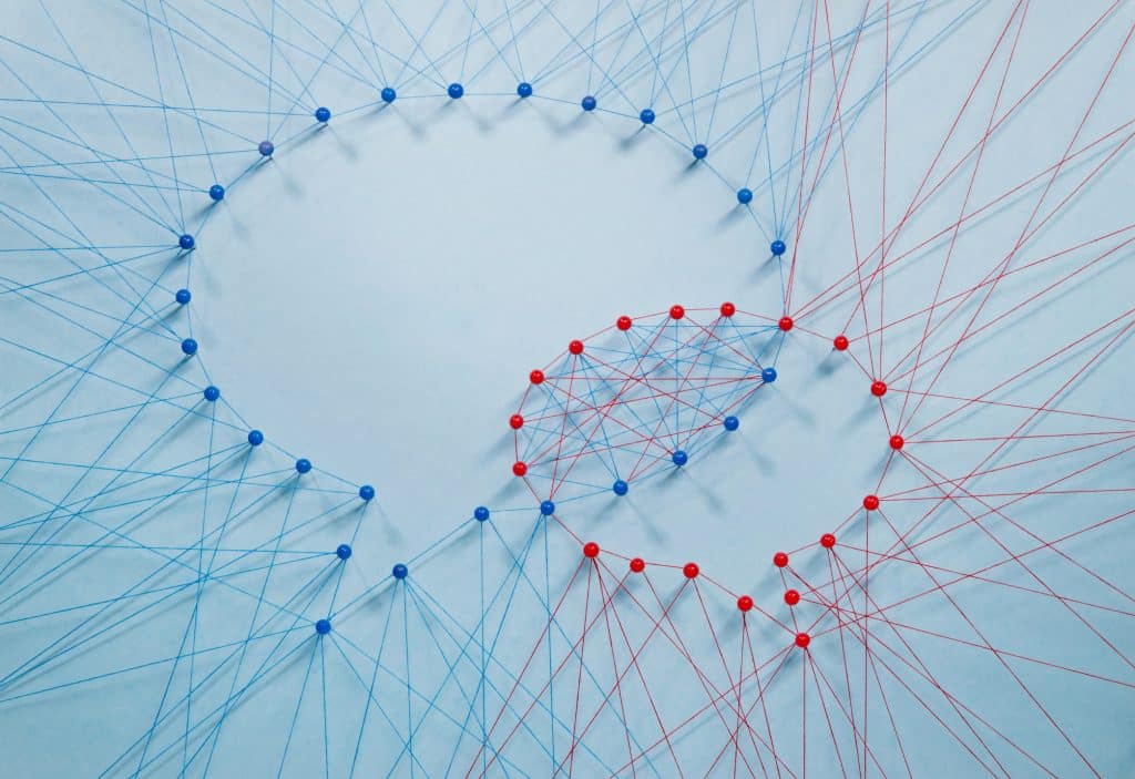 Red and blue threads and pins form two overlapping speech bubbles, representing psychological safety and the openness of a trusted team