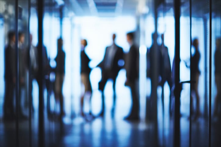 Blurred silhouettes of business partners interacting in corridor, symbolizing a lack of emotional intelligence in the workplace.